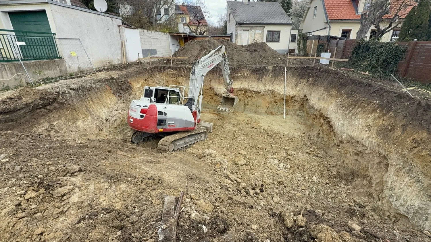 Bagger der EMK in einer frisch ausgehobenen Baugrube
