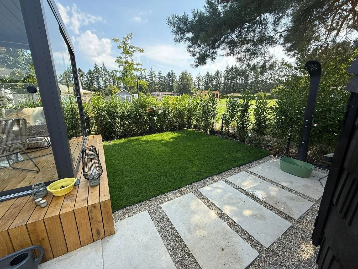Gartenweg aus großen Platten neben Rasen und Hecke